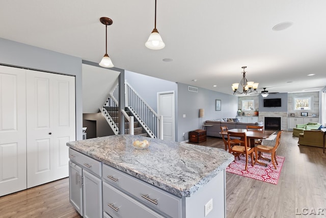 kitchen with a notable chandelier, visible vents, light wood-style flooring, and a fireplace