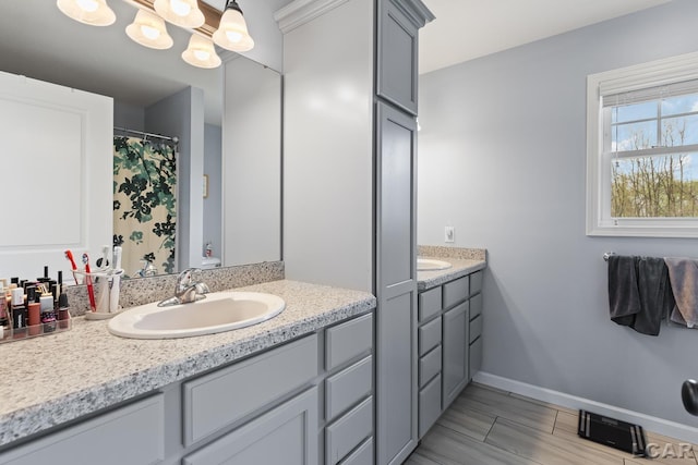 full bathroom featuring vanity, baseboards, and a notable chandelier