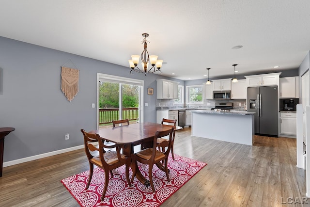 dining area featuring baseboards, recessed lighting, wood finished floors, and a notable chandelier