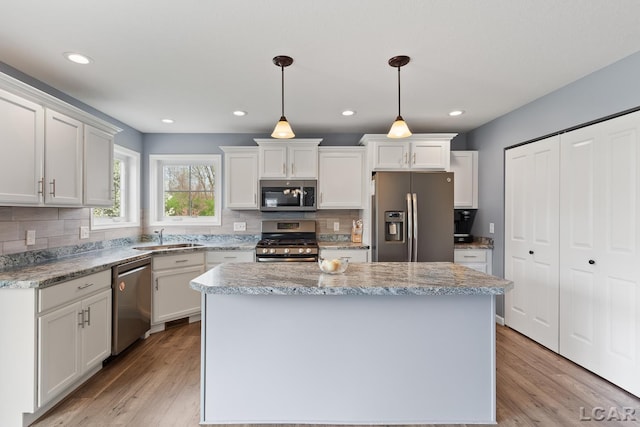 kitchen with white cabinets, appliances with stainless steel finishes, light wood finished floors, and a kitchen island