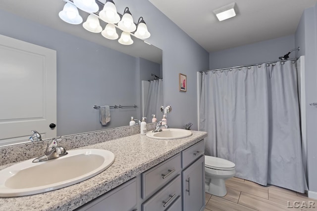 full bath with double vanity, toilet, a notable chandelier, and a sink
