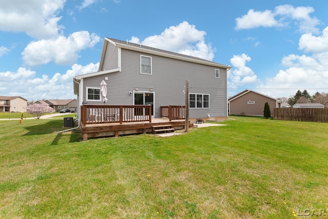 rear view of house featuring fence, a wooden deck, and a yard