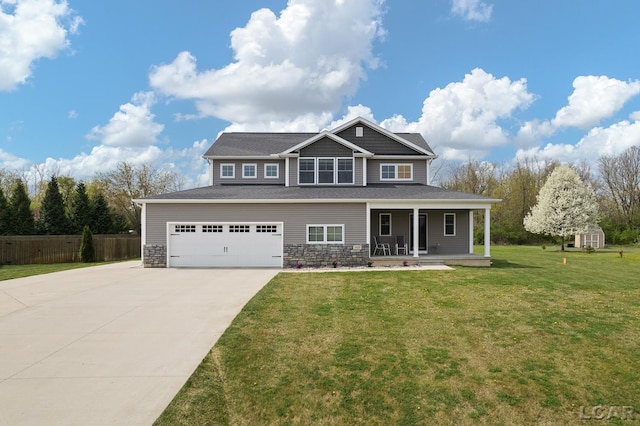 craftsman-style home featuring covered porch, fence, a front lawn, concrete driveway, and stone siding