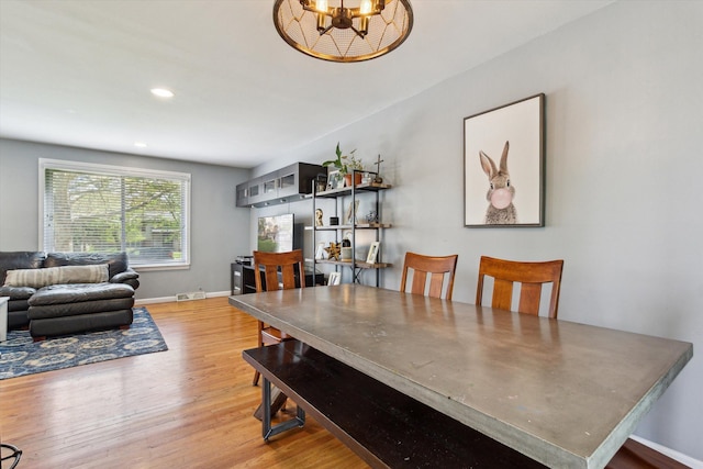 dining space with wood finished floors, baseboards, visible vents, recessed lighting, and a notable chandelier