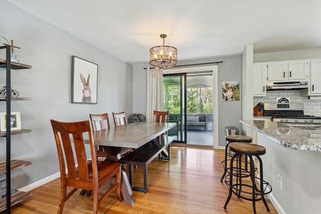 dining area featuring baseboards, light wood finished floors, and a chandelier