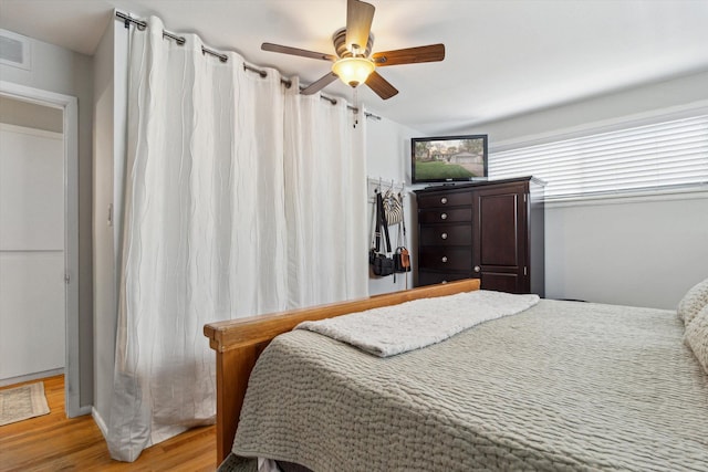 bedroom with a ceiling fan, visible vents, and wood finished floors