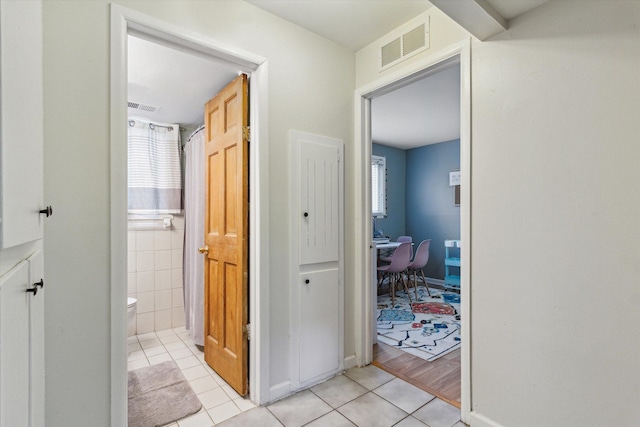 corridor featuring light tile patterned floors and visible vents