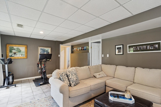 living area with light tile patterned flooring, a drop ceiling, baseboards, and visible vents