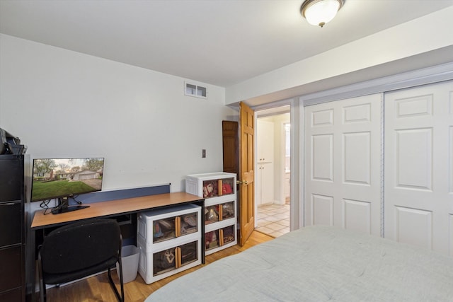 bedroom with light wood finished floors, a closet, and visible vents