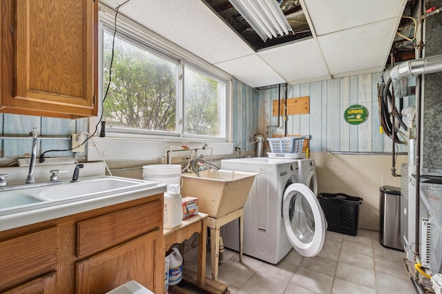 washroom with a sink, light tile patterned flooring, cabinet space, and independent washer and dryer