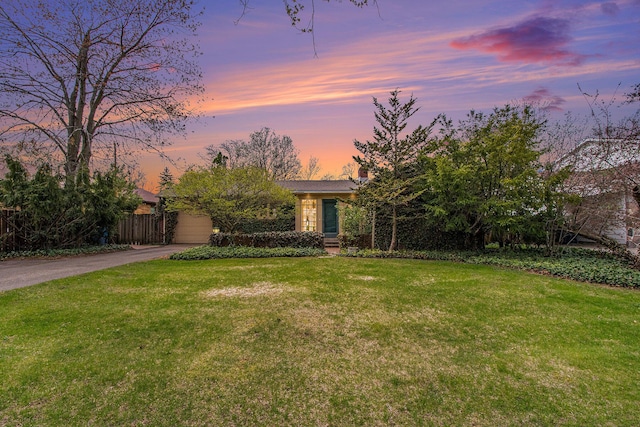 view of front of property featuring fence, driveway, a chimney, and a front lawn