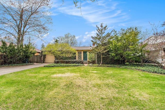 view of front of home with a front lawn, fence, driveway, and a chimney