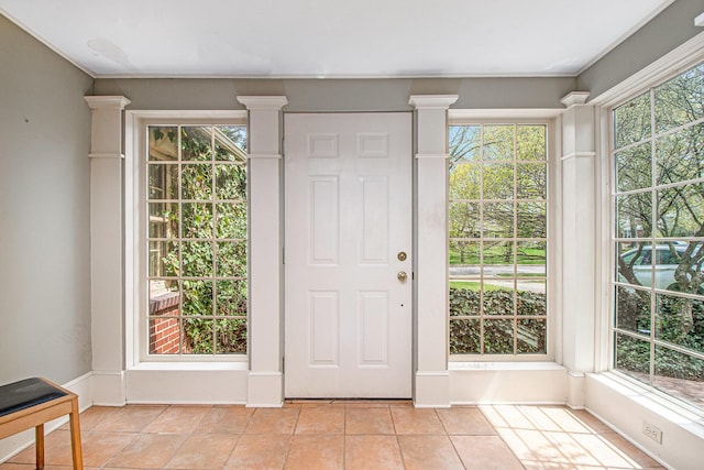 doorway to outside with ornate columns and light tile patterned floors