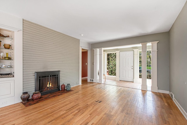 unfurnished living room with wood-type flooring, decorative columns, a fireplace, baseboards, and recessed lighting