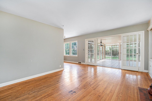 unfurnished living room featuring baseboards, visible vents, and hardwood / wood-style floors