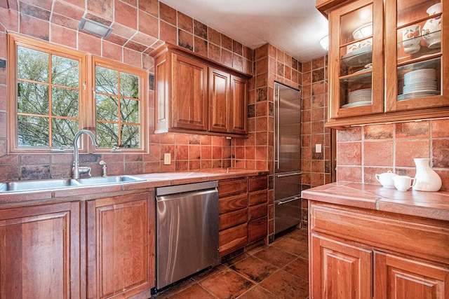 kitchen with a sink, decorative backsplash, appliances with stainless steel finishes, and tile countertops
