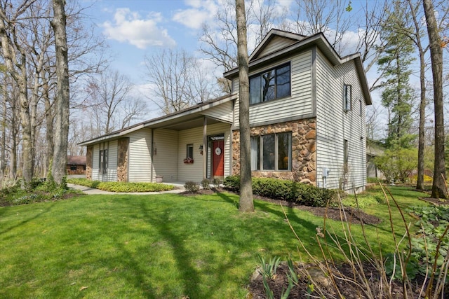 traditional-style home featuring a front yard and stone siding