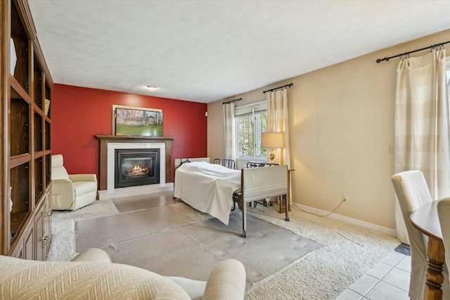 tiled bedroom featuring baseboards and a glass covered fireplace