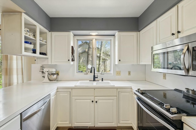 kitchen featuring a sink, appliances with stainless steel finishes, white cabinetry, and light countertops