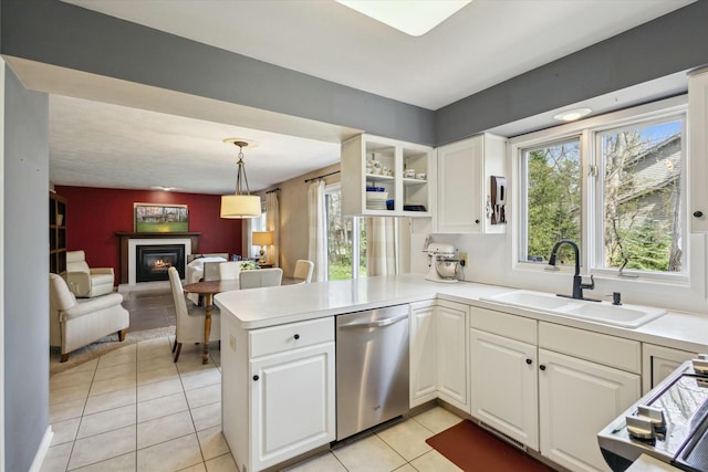kitchen with a sink, white cabinetry, a glass covered fireplace, and dishwasher
