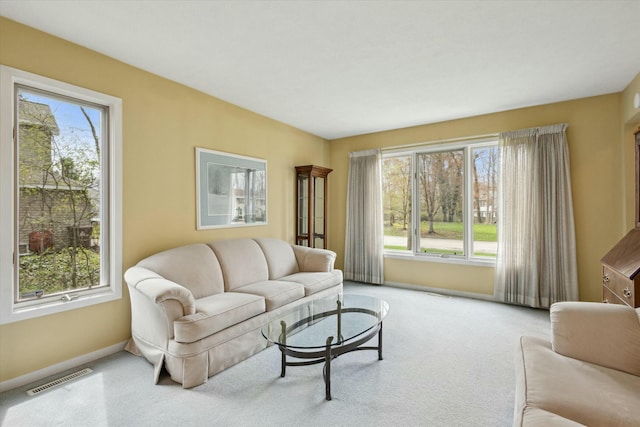 living room with visible vents, baseboards, carpet floors, and a wealth of natural light
