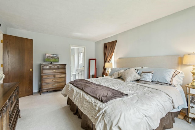 bedroom with light colored carpet and connected bathroom