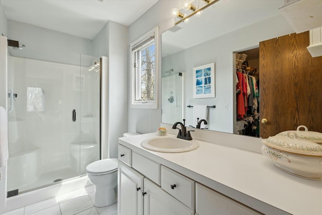 bathroom with toilet, a spacious closet, a shower stall, and vanity