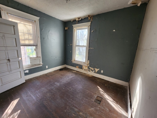 empty room with a textured ceiling, baseboards, and wood finished floors