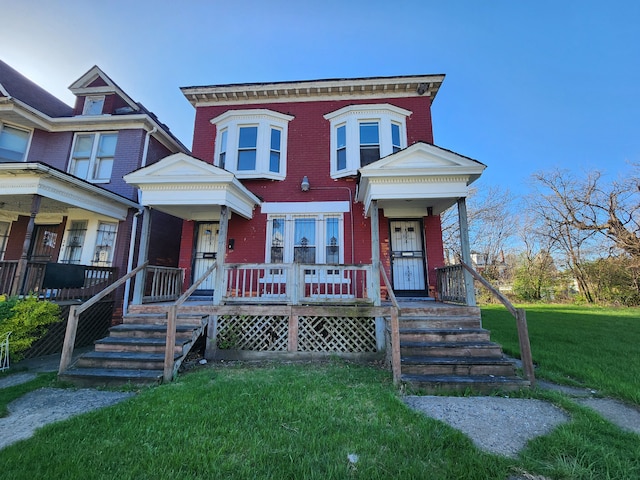 view of front facade featuring a porch, a front lawn, and brick siding