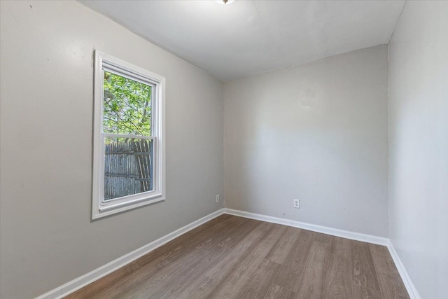 spare room with baseboards and wood finished floors