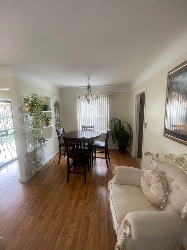 dining room featuring baseboards, an inviting chandelier, a healthy amount of sunlight, and wood finished floors