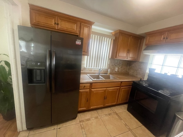 kitchen with light tile patterned flooring, a sink, a wealth of natural light, tasteful backsplash, and black appliances