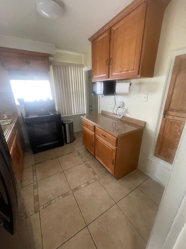 kitchen featuring light tile patterned floors, light countertops, and brown cabinetry