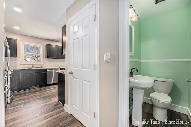 bathroom with a sink, backsplash, wood finished floors, and toilet
