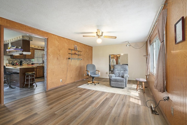 living area featuring a ceiling fan, a textured ceiling, and wood finished floors