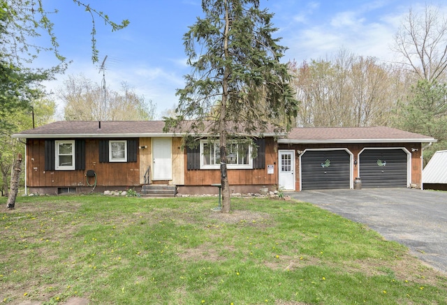 ranch-style home featuring a front yard, an attached garage, entry steps, and aphalt driveway