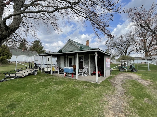 rear view of property with a yard, a chimney, and metal roof