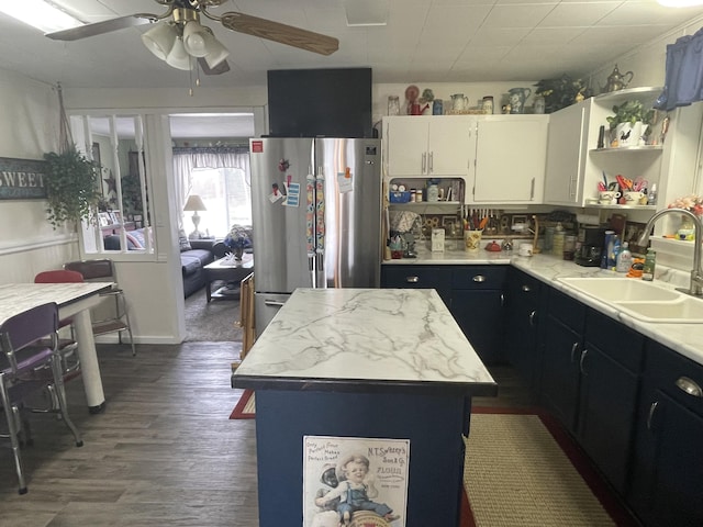kitchen featuring freestanding refrigerator, a ceiling fan, wood finished floors, light countertops, and a sink