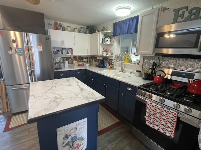 kitchen featuring open shelves, a kitchen island, dark wood-style floors, a sink, and appliances with stainless steel finishes