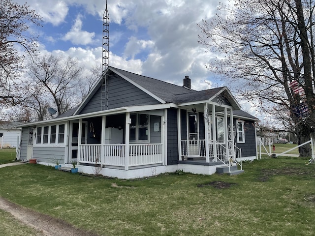 bungalow with covered porch, a chimney, roof with shingles, and a front lawn