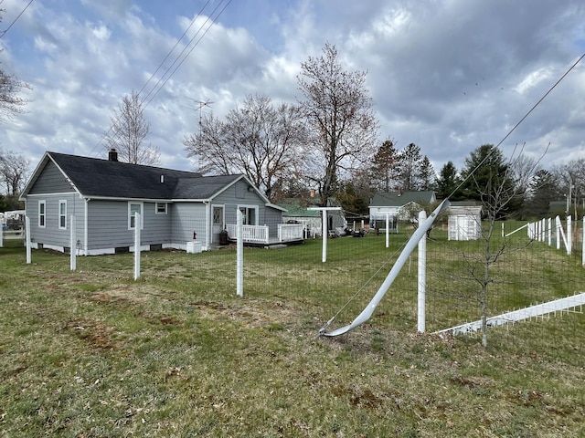 rear view of property featuring a lawn, a wooden deck, and roof with shingles