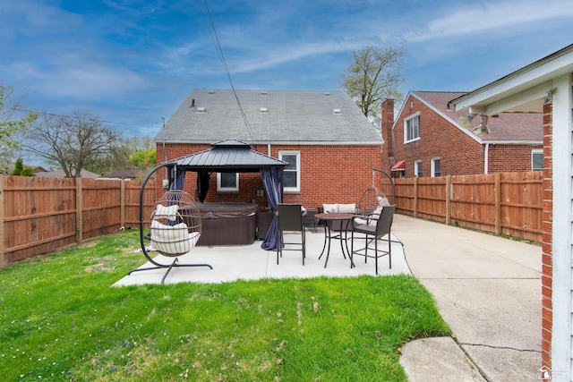 rear view of property with a gazebo, a hot tub, brick siding, a fenced backyard, and a patio