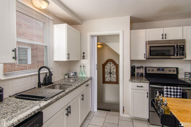 kitchen with a sink, appliances with stainless steel finishes, backsplash, and white cabinets