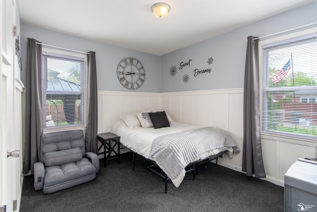 carpeted bedroom with a wainscoted wall and a decorative wall