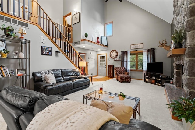 carpeted living room with high vaulted ceiling and stairs