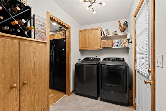 laundry room with independent washer and dryer, a chandelier, and cabinet space
