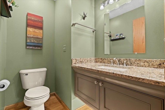 bathroom with toilet, baseboards, wood finished floors, and vanity