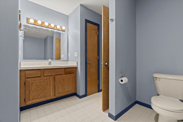 bathroom featuring vanity, baseboards, tile patterned flooring, and toilet