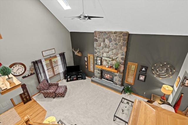 living area featuring a ceiling fan, a fireplace, wood finished floors, high vaulted ceiling, and baseboards