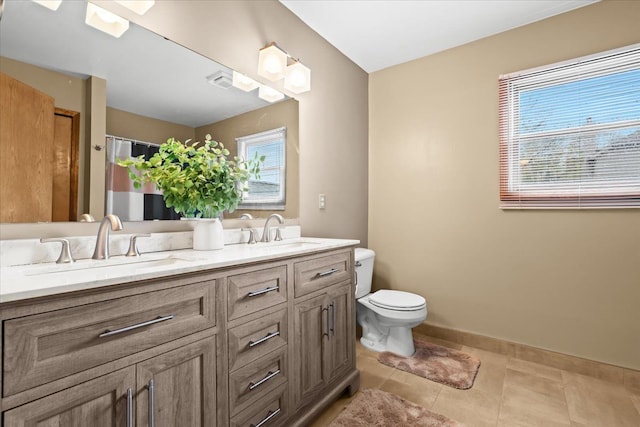 bathroom with a sink, tile patterned floors, toilet, and double vanity